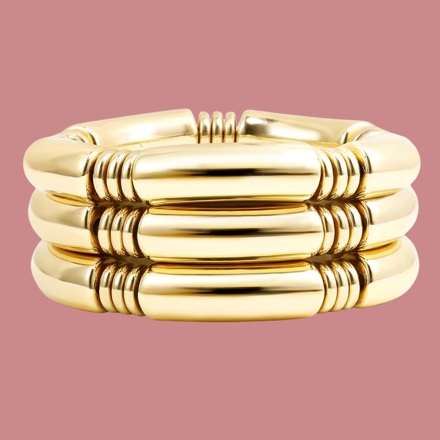 Gold tube stretch bracelet set, featuring three stacked bracelets with a smooth, shiny finish against a pink background.