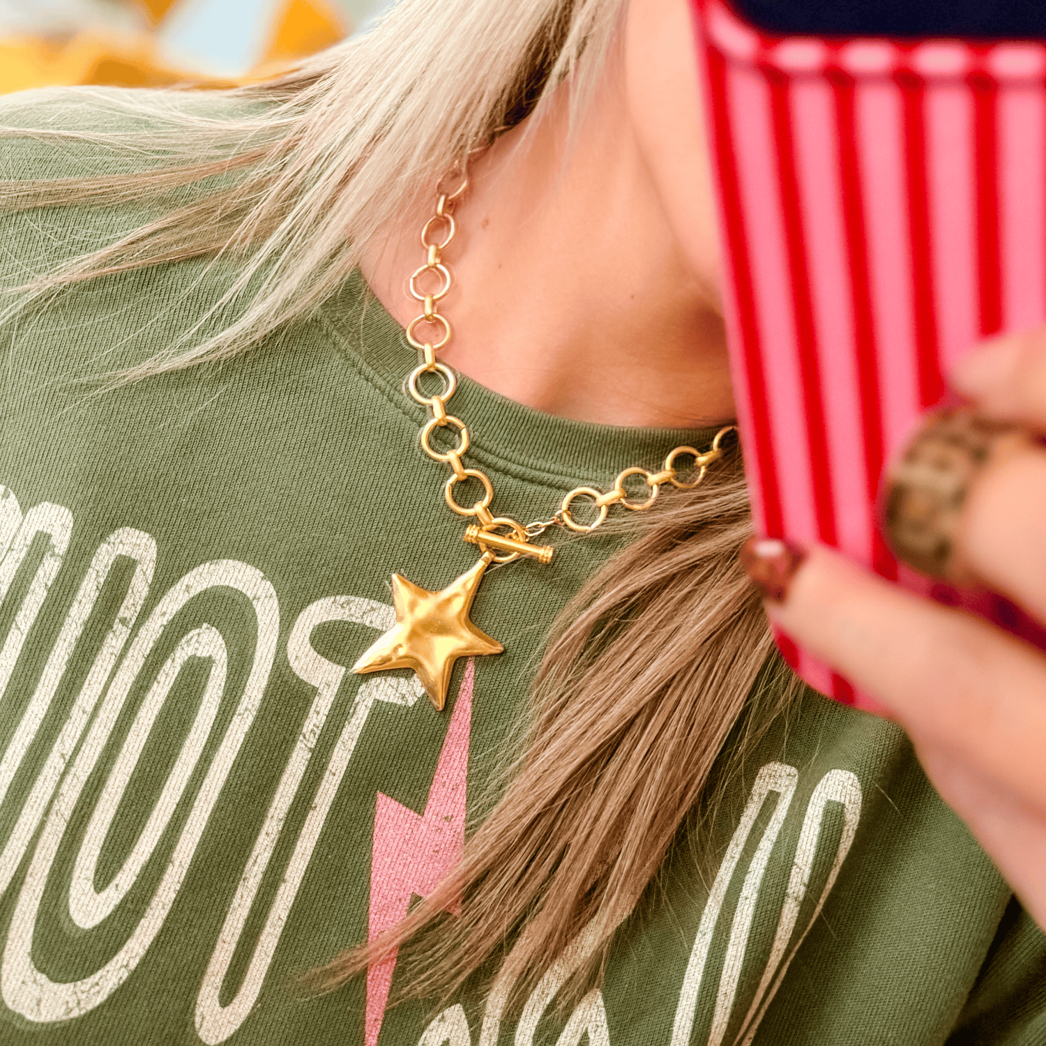 Gold star charm necklace with a chunky chain, worn by a person in a green shirt, reflecting a casual style.