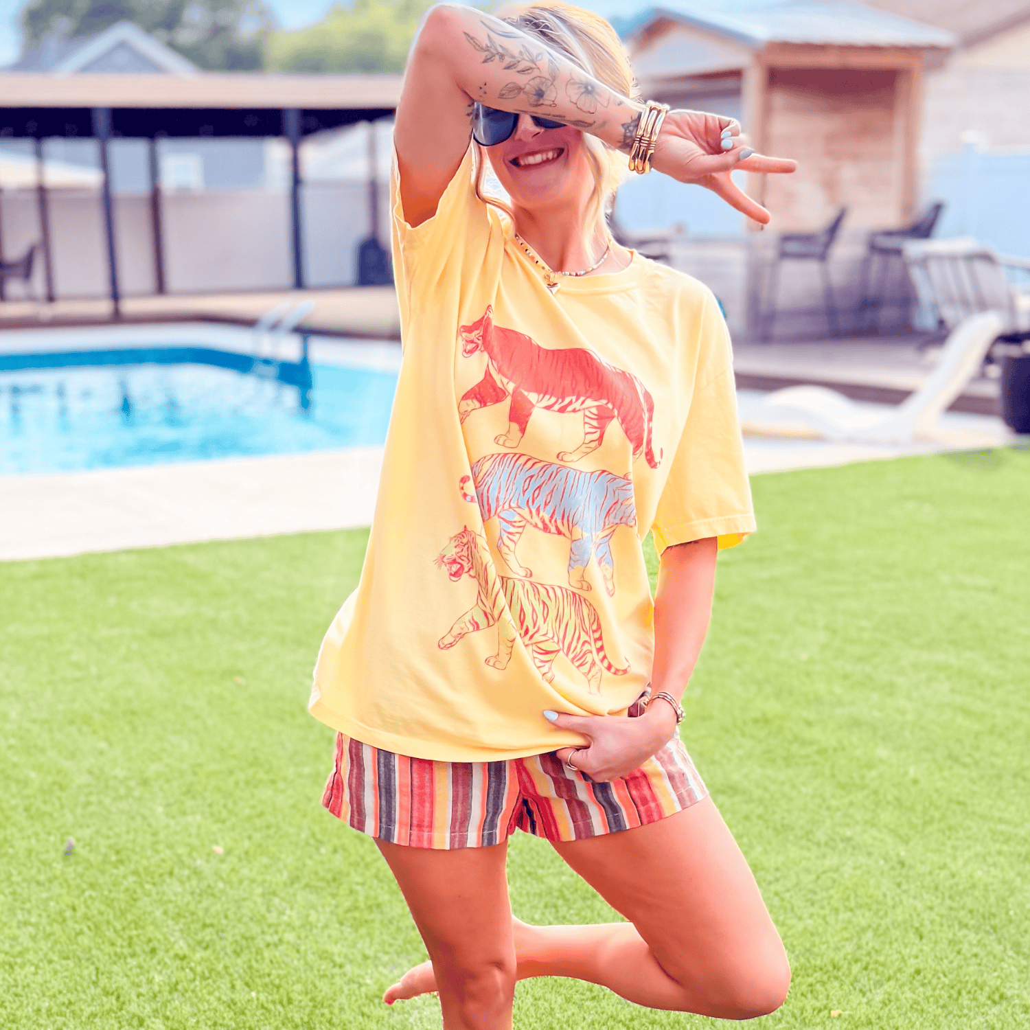 Yellow Neon Tigers Tee featuring colorful tiger graphics, worn by a person outdoors near a pool.