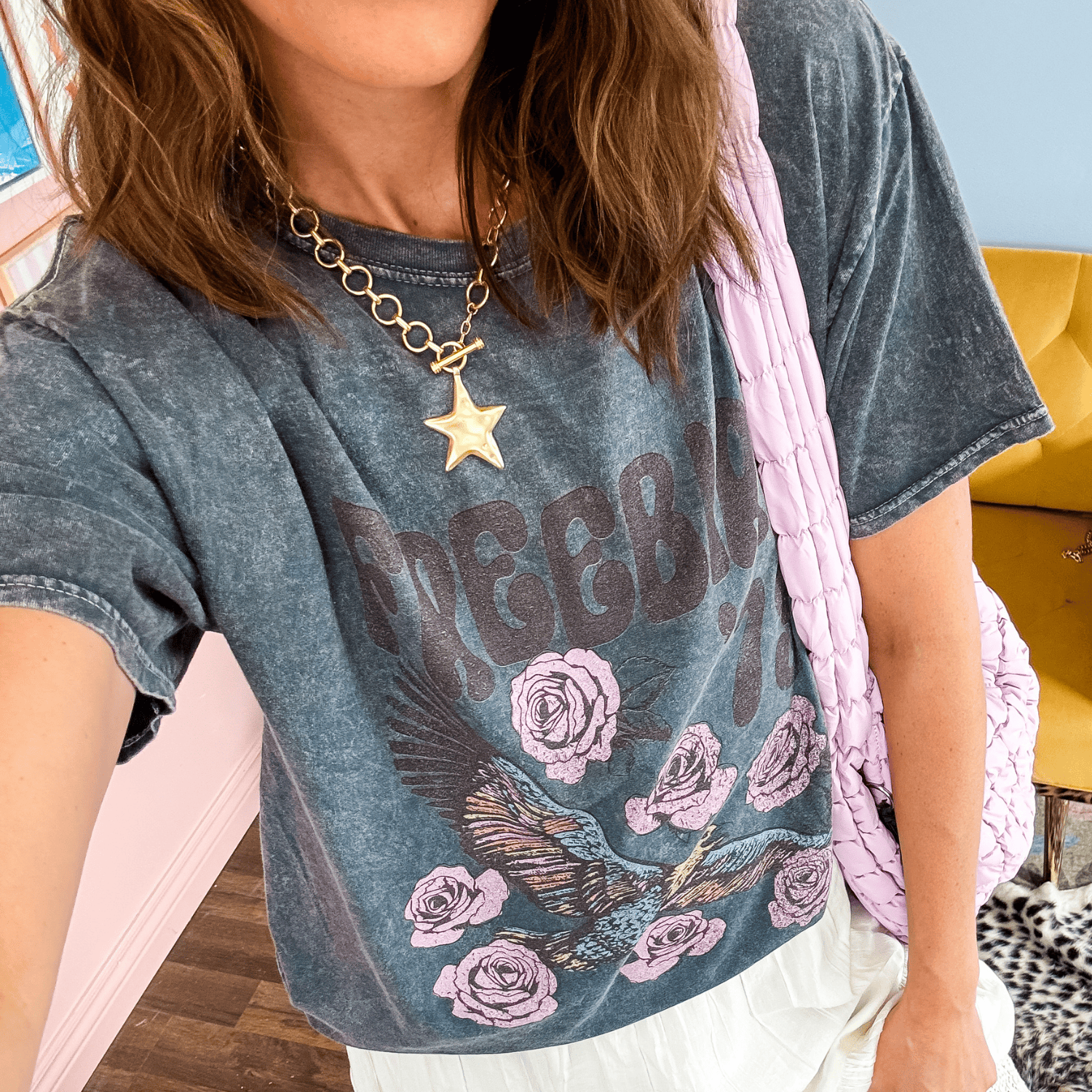 Gold star charm necklace worn with a faded graphic t-shirt featuring roses and an eagle design.
