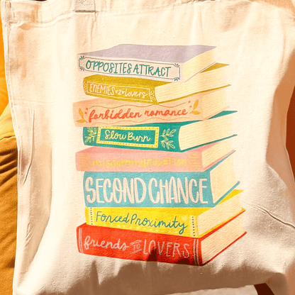 Trope Tote featuring colorful stacked book illustrations with titles like "Opposites Attract" and "Second Chance.